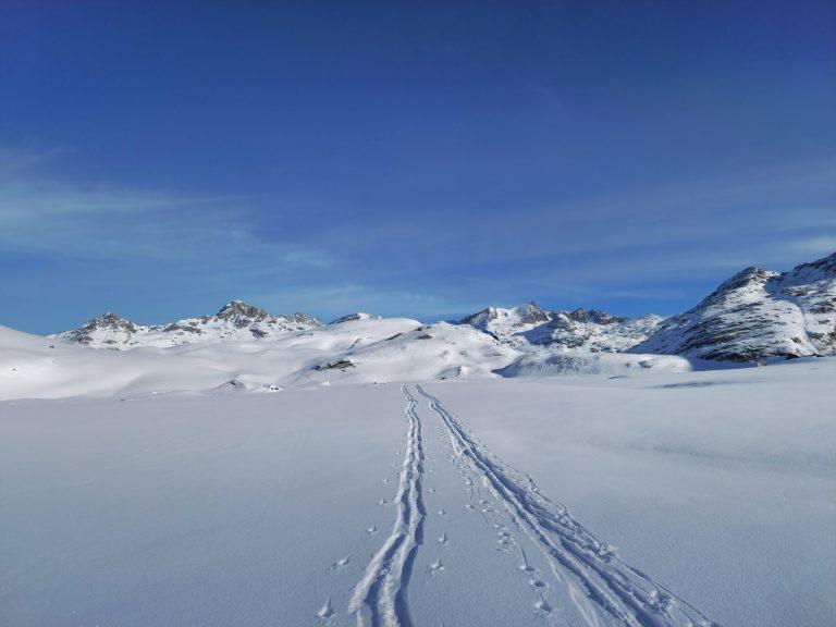 Trace de ski traversant un plateau neigeux au-dessus d'une mer de nuages