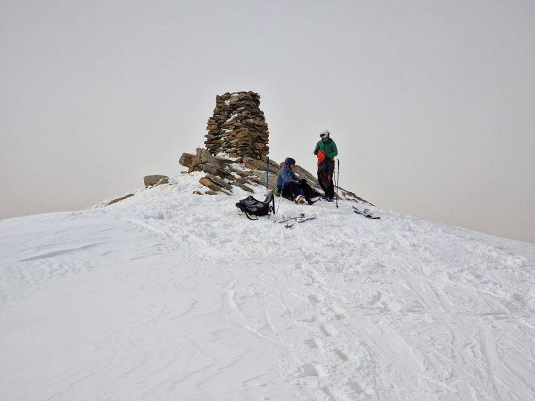 Cairn sommital et skieur dans la brume