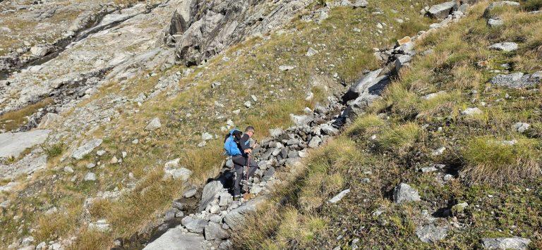 Randonneurs remontant un torrent entre dalles et herbes rousses d'automne