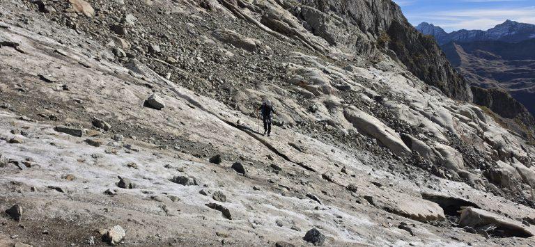 Randonneur traversant un reste de glacier gelé et crevassé, sur une trentaine de mètres