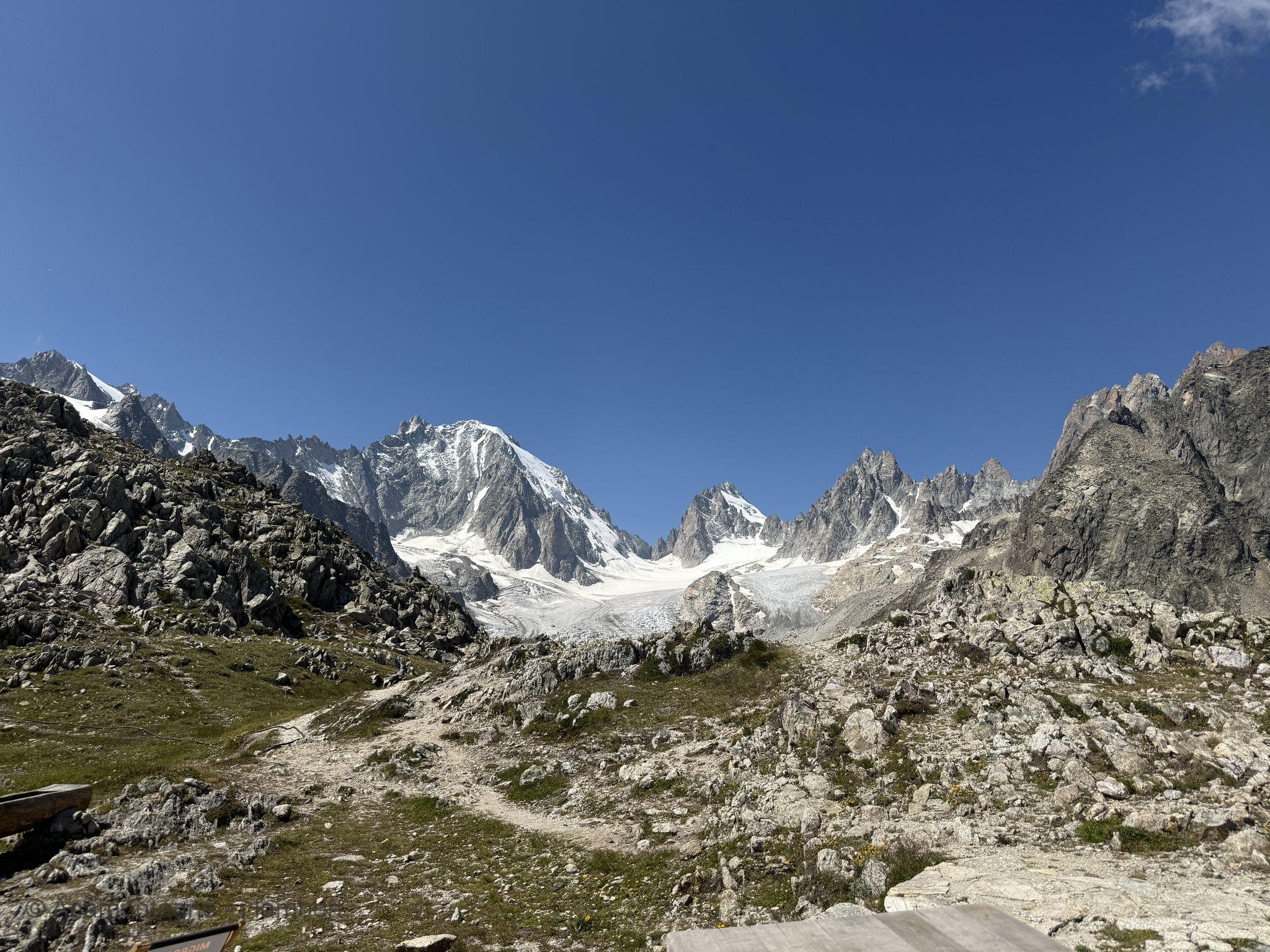 Sentier dans les rochers près de la cabane de Saleinaz, face au bassin glaciaire et aux sommets enneigés