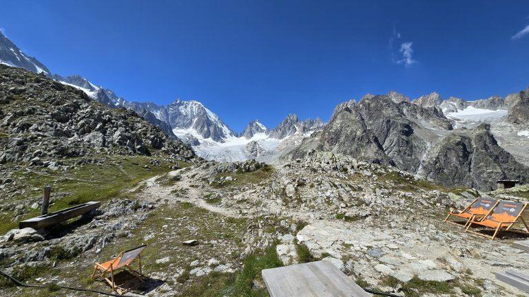 Chaises longues orange sur la terrasse rocheuse de la cabane, face au bassin glaciaire