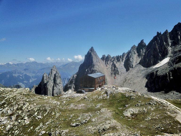 Vue au drone de la cabane sur son replat herbeux, avec les Clochers des Planereuses en arrière-plan