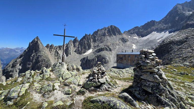 Croix et cairns sur la butte au-dessus de la cabane, sommets rocheux en arrière-plan