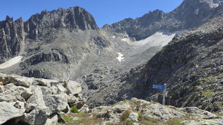 Panneau indicateur sur les dalles, sous les tours rocheuses et un névé