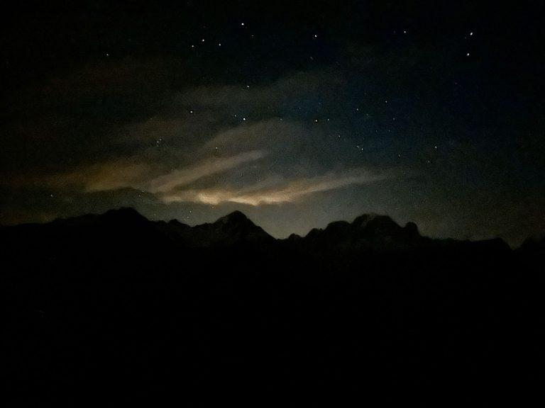 Ciel étoilé et nuages éclairés au-dessus des crêtes, de nuit depuis le refuge de Loriaz