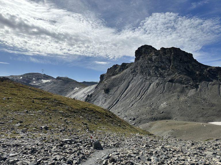 Éperon de roche sombre au-dessus d'un pierrier, sous un ciel pommelé