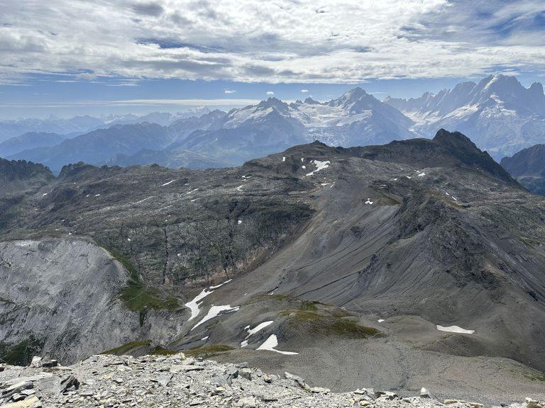 Crêtes grises et névés sous le Cheval Blanc, le massif du Mont-Blanc à l'horizon