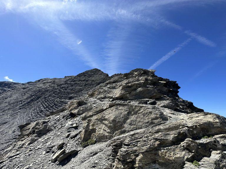 Ressaut de schiste feuilleté sur l'arête, sous un ciel strié de traînées