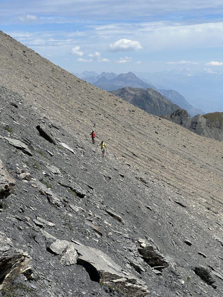 Deux randonneurs traversent une vaste pente de schiste