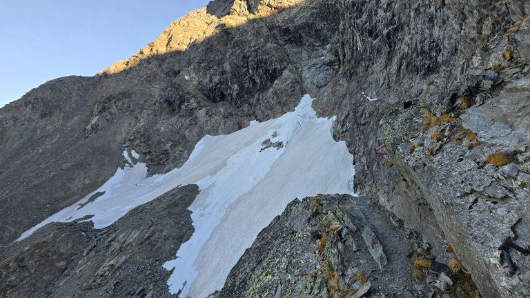 Névé entre les rochers schisteux, balisage rouge à droite