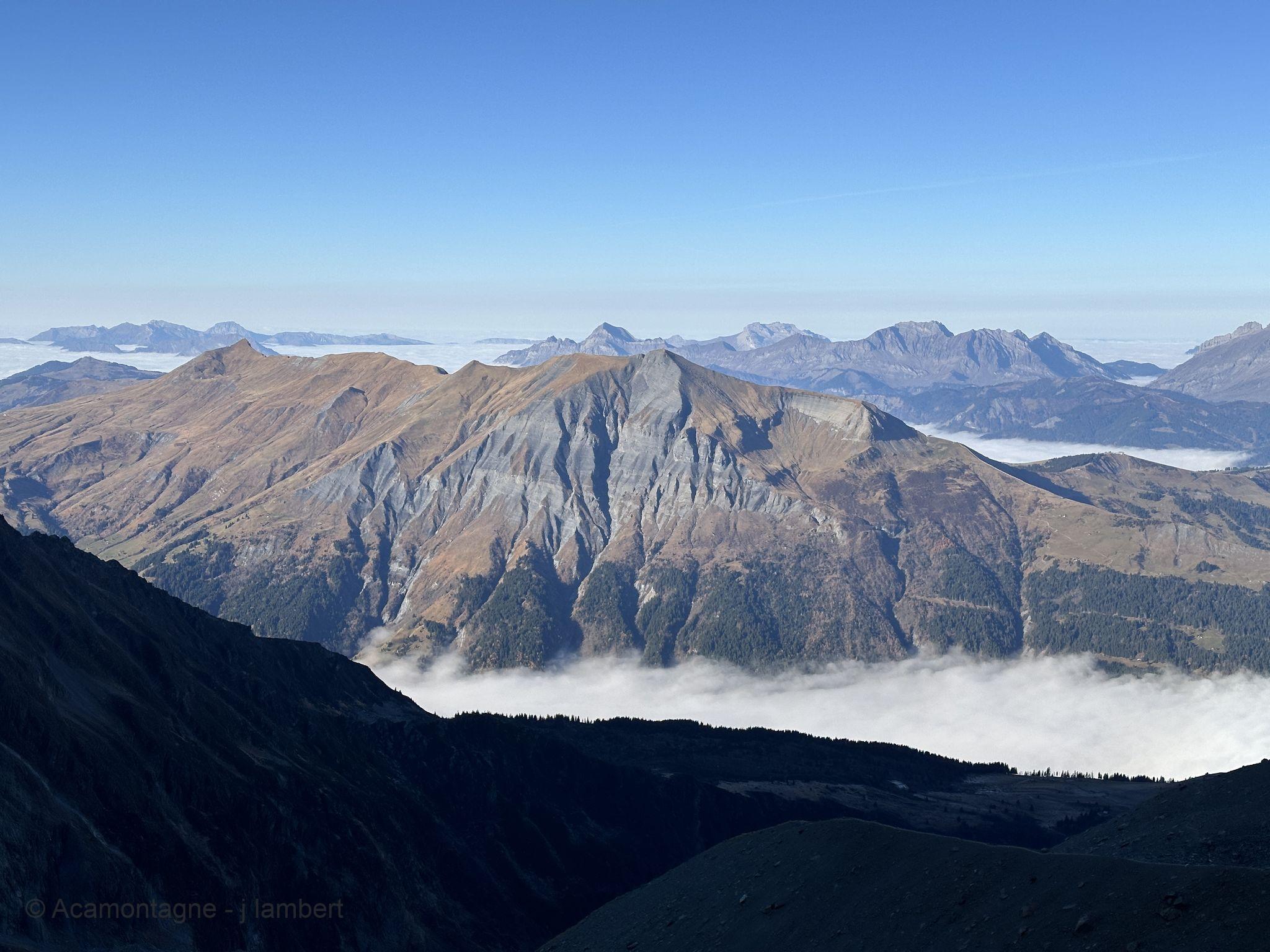 Sommets dorés et chaînes lointaines au-dessus de la mer de nuages, sous un ciel bleu