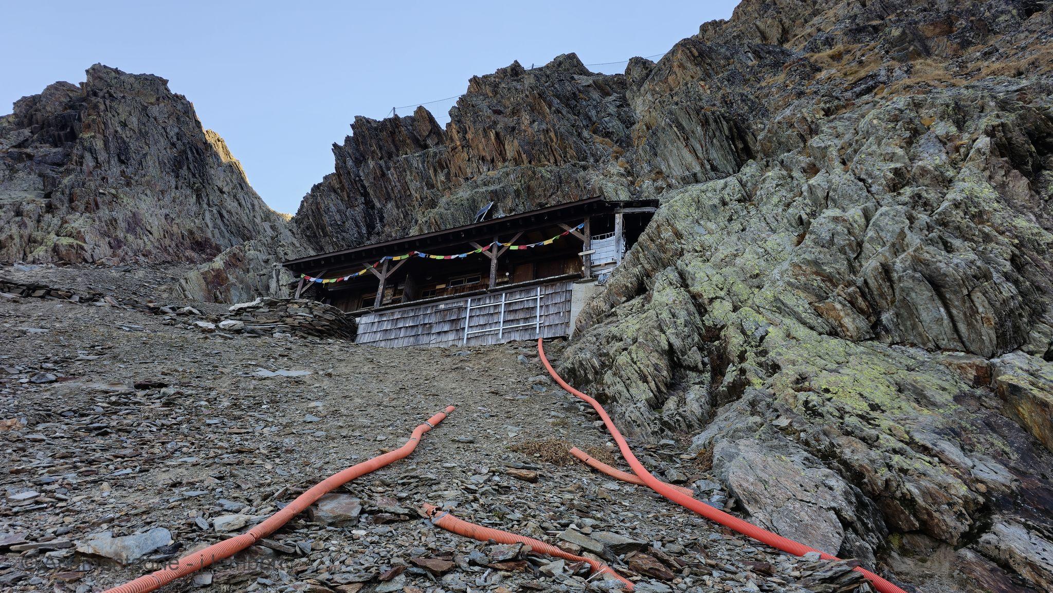 Le refuge de Plan Glacier niché entre les rochers, drapeaux de prière tendus sur la façade