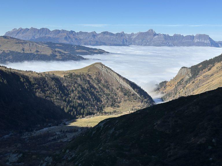 Mer de nuages sur la vallée, une longue chaîne calcaire au loin, le vallon de Miage à l'ombre au premier plan