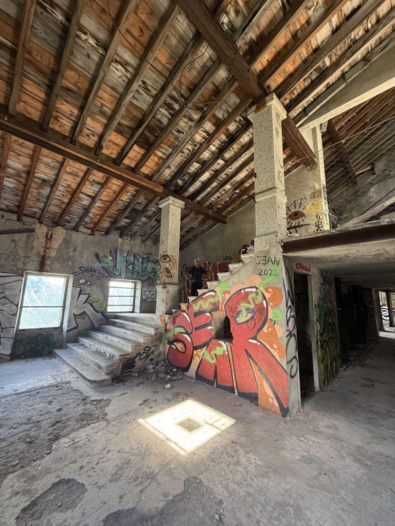 Hall de transfert de La Para sous une charpente en bois, escalier et murs couverts de graffitis
