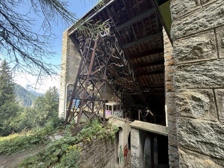 Maçonnerie de pierre et charpente métallique rouillée de la gare de La Para, au milieu des mélèzes