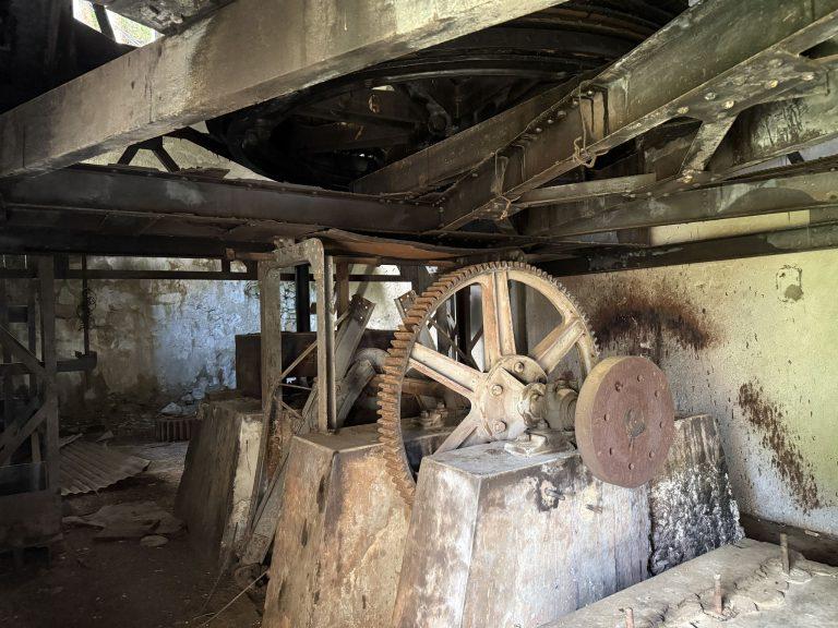 Grande roue dentée et volant de l'ancienne machinerie du téléphérique, dans la pénombre de la gare