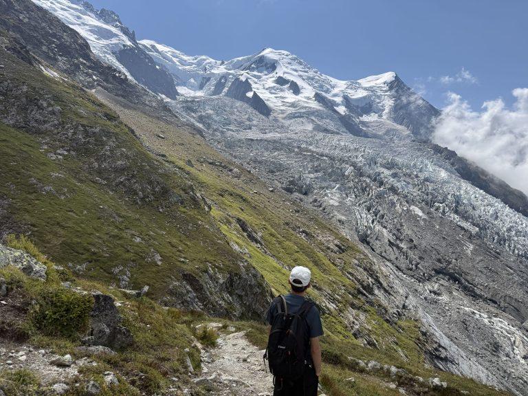 Randonneur sur le sentier, face au Mont Blanc et au glacier des Bossons