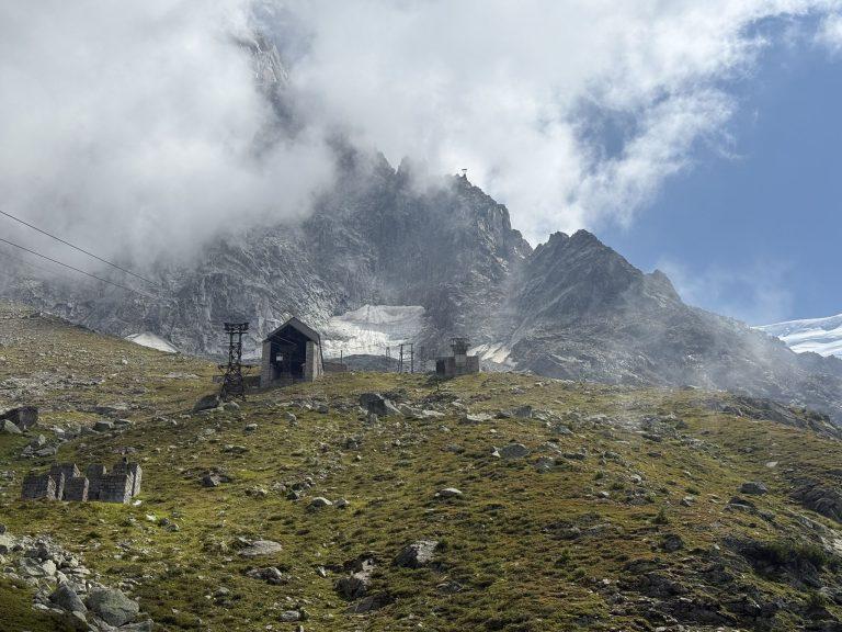 Bâtiment, pylône et ruines de l'ancienne ligne sur l'alpage, sous l'Aiguille du Midi prise dans les nuages