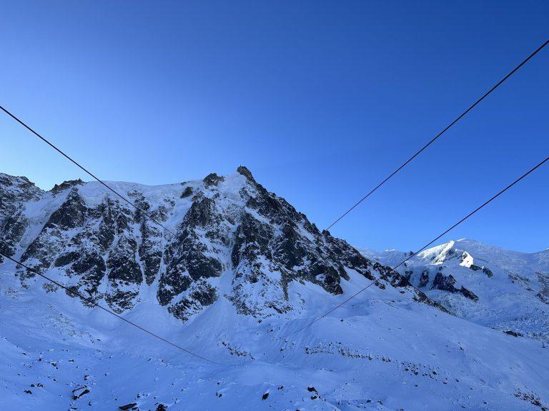 Câbles du téléphérique de l'Aiguille du Midi tendus au-dessus des pentes enneigées et des parois de granit