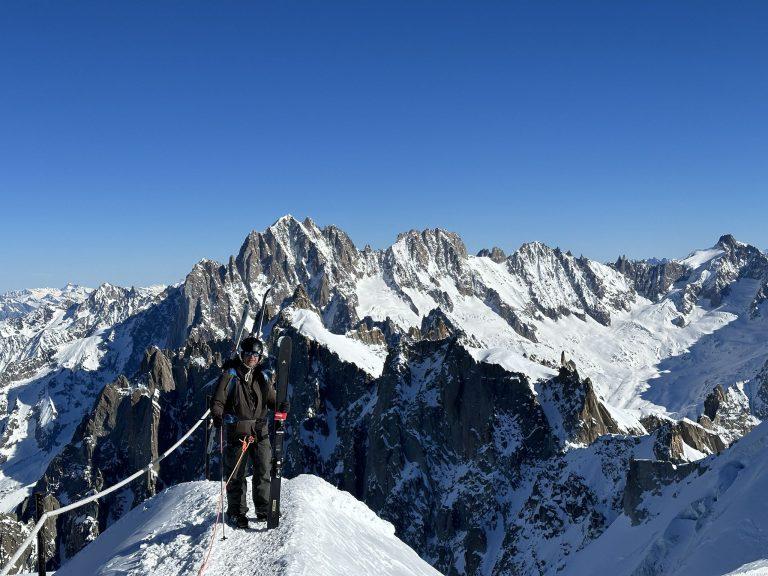Skieur sur l'arête de l'Aiguille du Midi, skis sur le sac, face aux sommets enneigés