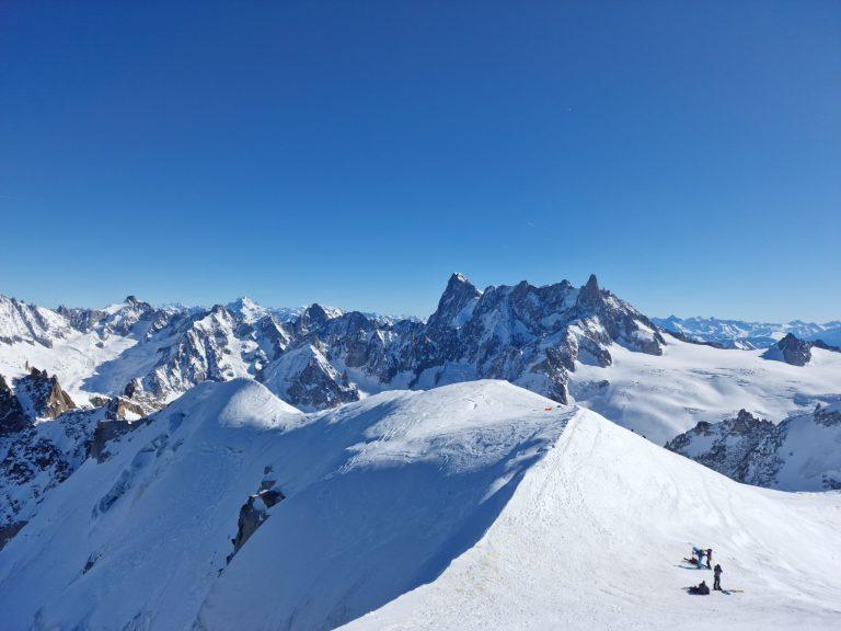 Skieurs au pied de l'arête, la Dent du Géant et les sommets vers l'Italie à l'horizon