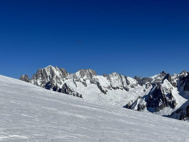 Crêtes enneigées et aiguilles de granit au-delà d'une pente de neige