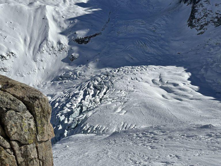 Vue plongeante sur les crevasses du glacier, un rocher au premier plan